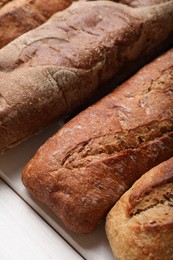 Photo of Different tasty baguettes on white wooden table, closeup