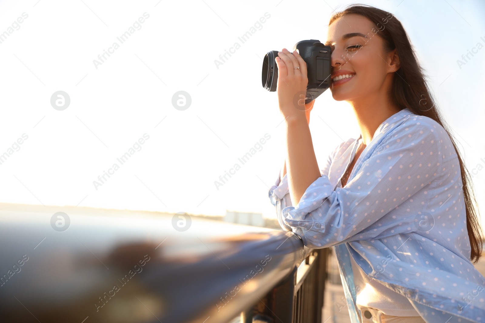 Photo of Young photographer taking picture with professional camera outdoors. Space for text