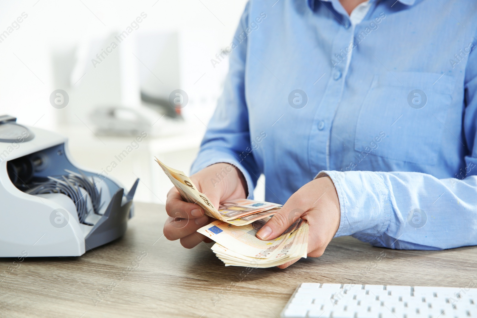 Photo of Female teller counting money at cash department, closeup