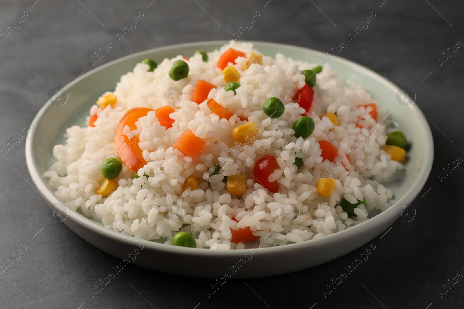 Photo of Delicious rice with vegetables on grey table, closeup