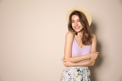 Young woman wearing floral print skirt and straw hat on beige background. Space for text