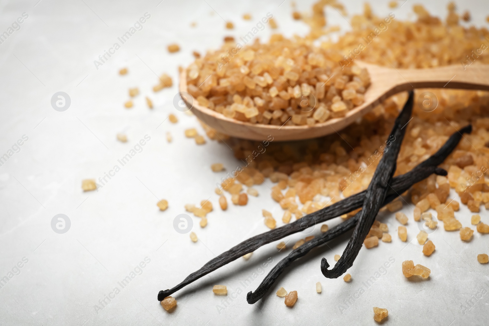 Photo of Spoon with aromatic vanilla sugar and sticks on grey background