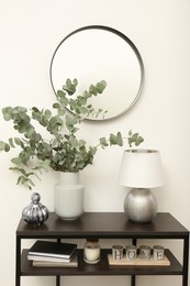 Photo of Modern console table with stylish decor and mirror on white wall in room. Interior design