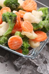 Mix of different frozen vegetables with ice on grey table, closeup