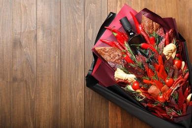 Photo of Beautiful edible bouquet with meat, cheese and vegetables on wooden table, top view. Space for text