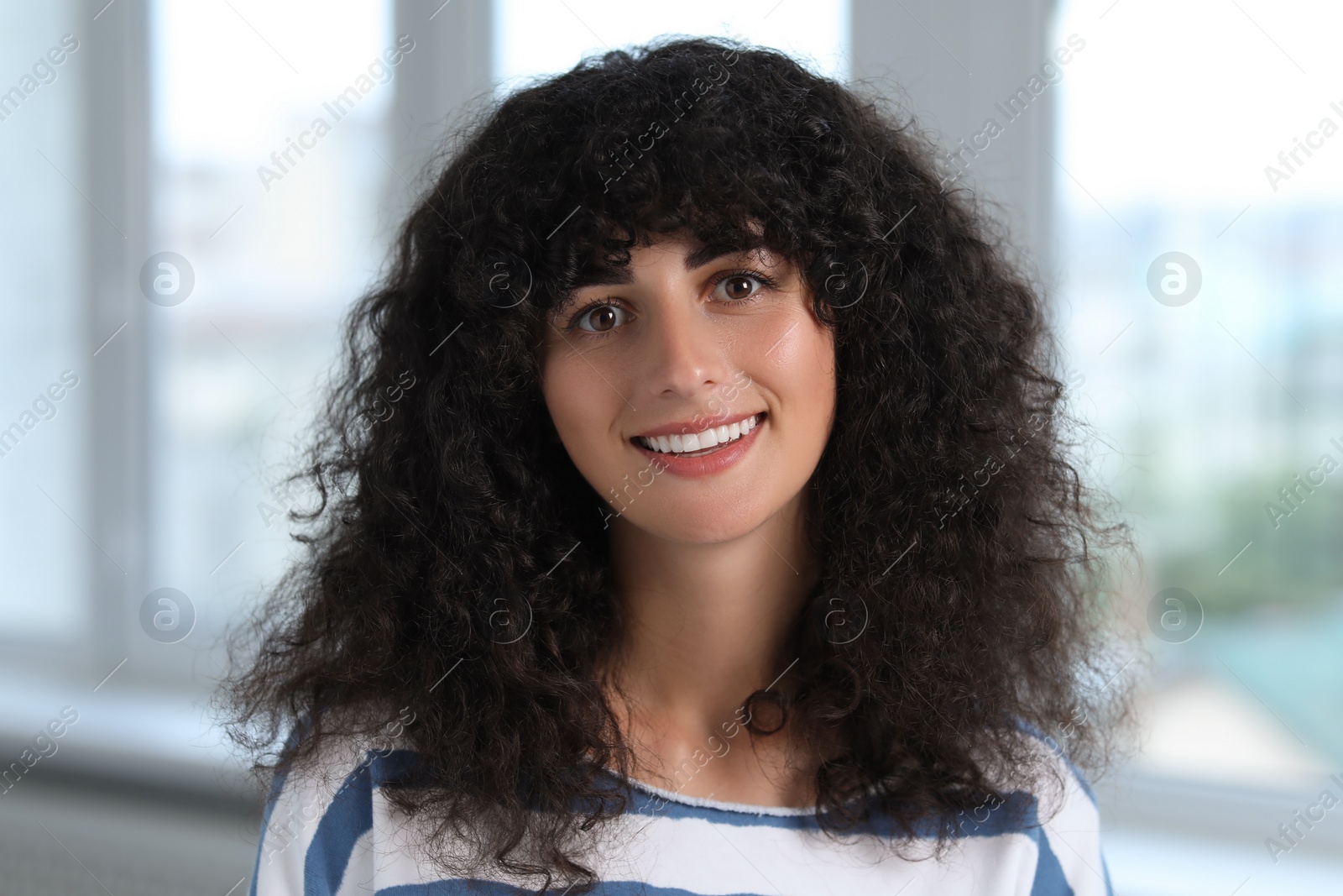 Photo of Portrait of beautiful woman in glasses indoors. Attractive lady with curly hair looking into camera