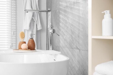 Photo of Different personal care products and accessories on bath tub in bathroom