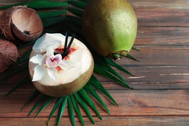 Photo of Fresh green coconuts and palm leaf on wooden table