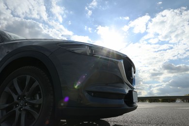 Photo of New black modern car against cloudy sky on sunny day, closeup