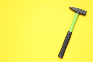 New hammer with rubber handle on yellow background, top view. Space for text