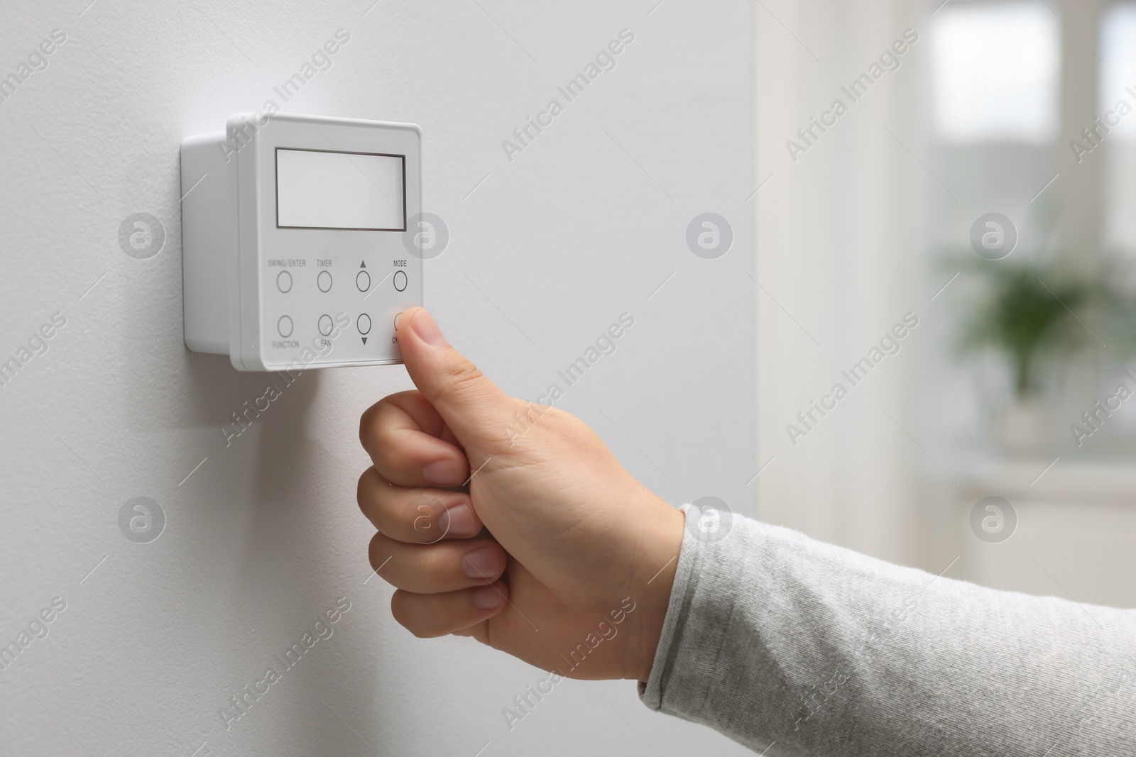 Photo of Woman adjusting thermostat on white wall indoors, closeup. Smart home system