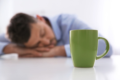 Photo of Man sleeping at home in morning, focus on cup