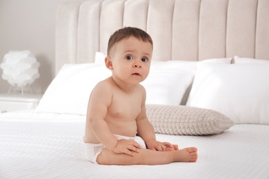 Cute baby in dry soft diaper on white bed at home