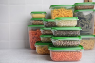 Plastic containers filled with food products on white table near tiled wall. Space for text