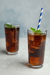 Refreshing soda drinks with straw on grey table against blue background