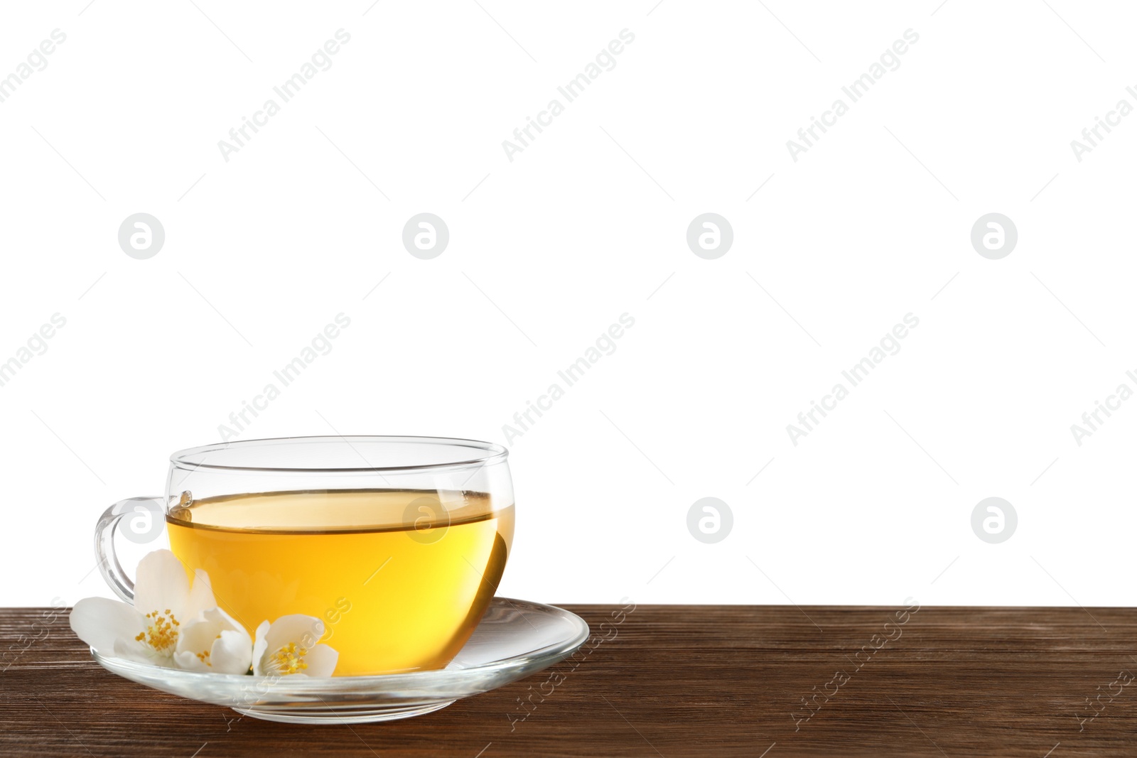 Photo of Glass cup of aromatic jasmine tea and fresh flowers on wooden table against white background. Space for text