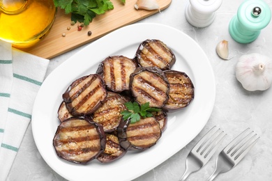 Delicious grilled eggplant slices served on grey table, flat lay
