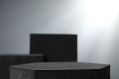 Photo of Black geometric figures on light grey background, closeup. Stylish presentation for product