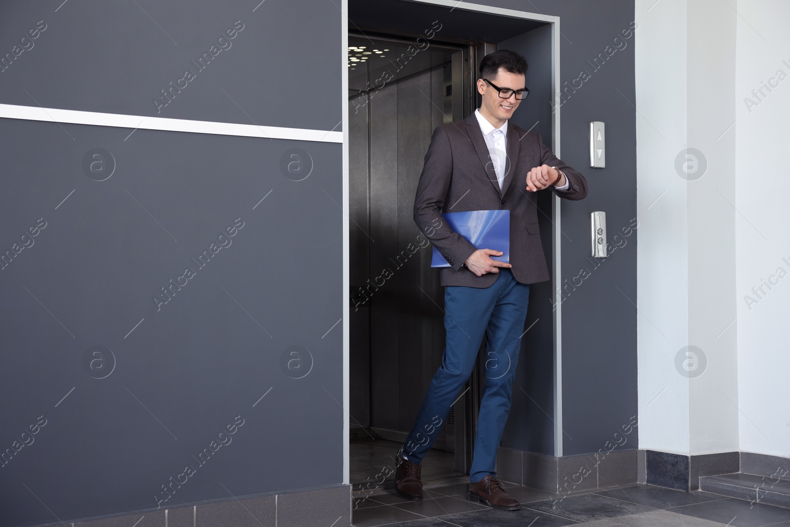 Photo of Young businessman walking out of modern elevator