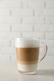 Hot coffee with milk in glass cup on white wooden table