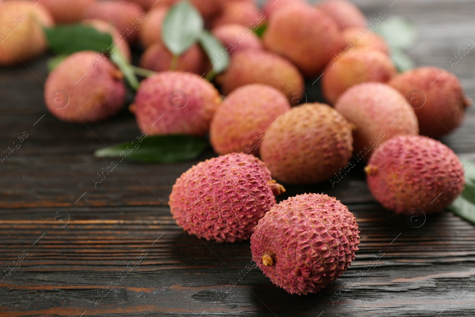 Photo of Fresh ripe lychee fruits on dark wooden table. Space for text