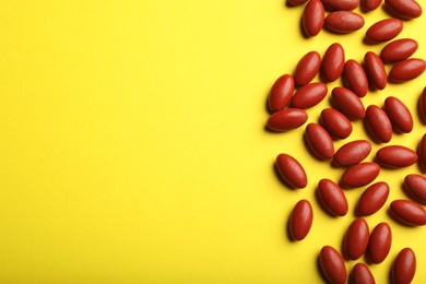 Photo of Red pills on yellow background, flat lay with space for text. Anemia treatment