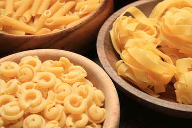 Photo of Different types of pasta in bowls on table, closeup