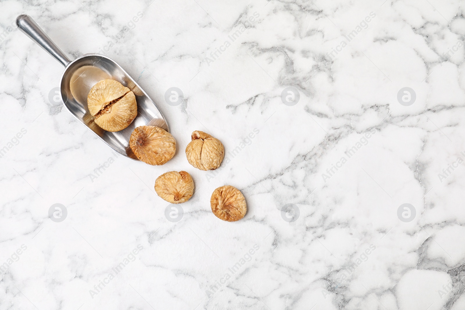 Photo of Scoop of dried figs on marble table, top view with space for text. Healthy fruit