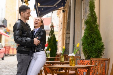 Photo of Lovely young couple enjoying time together in outdoor cafe. Romantic date