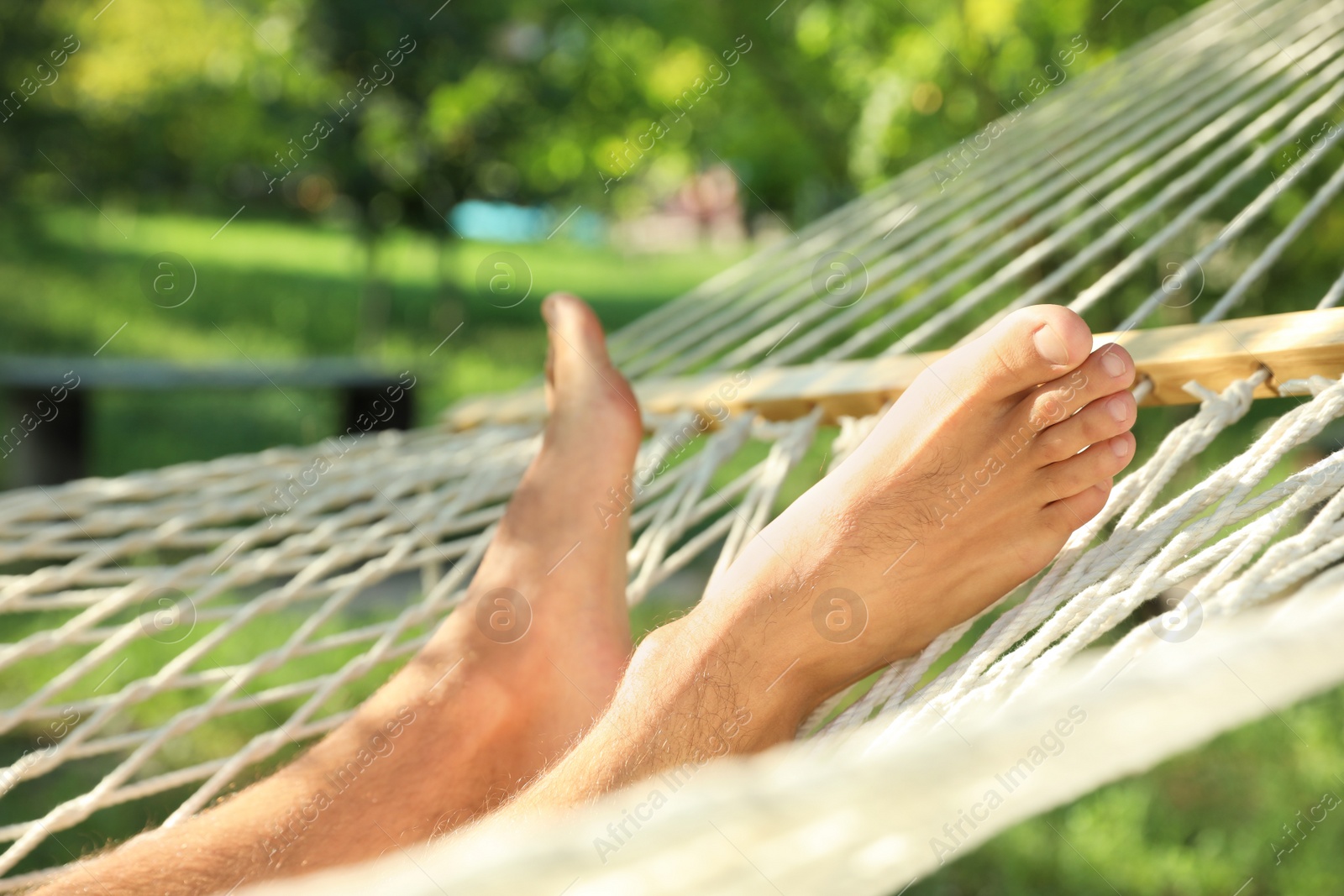 Photo of Young man resting in comfortable hammock at green garden, closeup