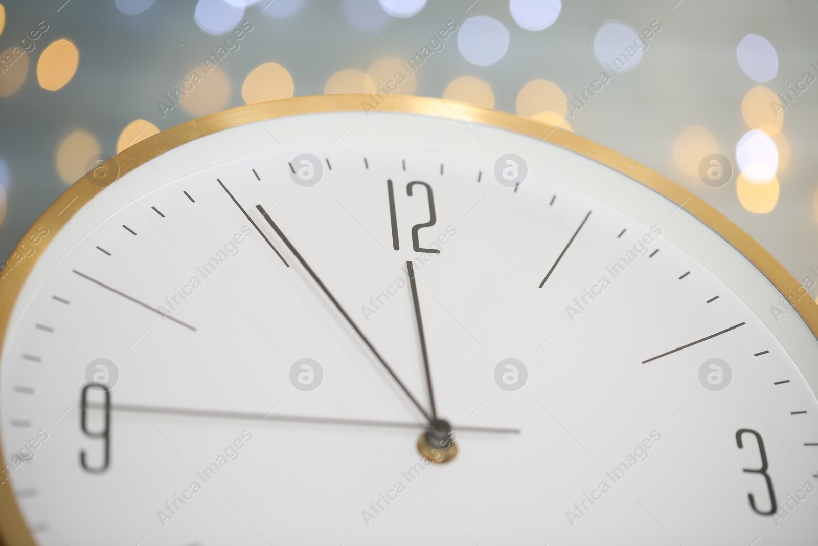 Photo of Clock showing five minutes until midnight on blurred background, closeup. New Year countdown