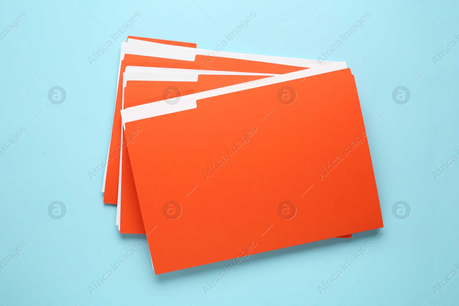 Photo of Orange files with documents on light blue background, top view