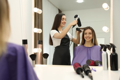 Photo of Stylist drying client's hair in beauty salon