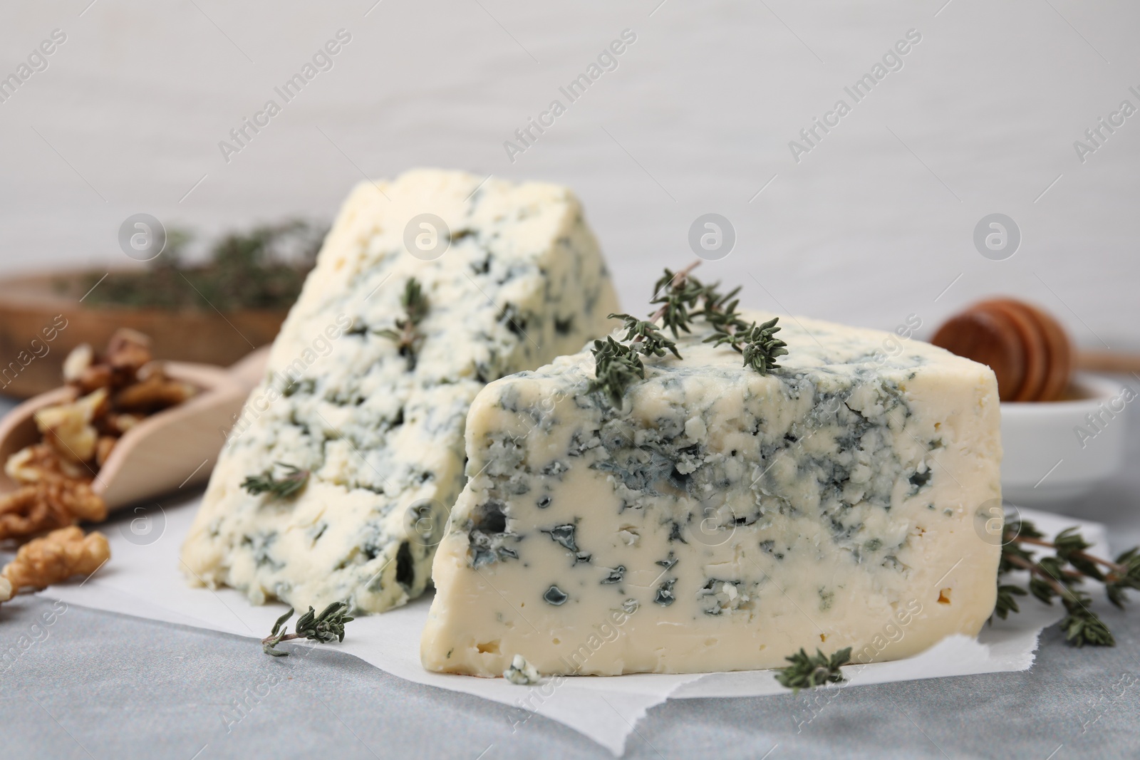 Photo of Tasty blue cheese with thyme on grey table, closeup