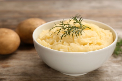 Photo of Bowl with mashed potatoes on wooden table