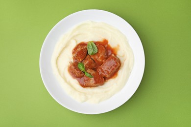 Delicious goulash with mashed potato on green background, top view