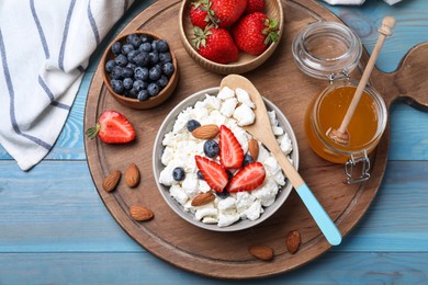 Photo of Bowl of fresh cottage cheese, berries with almond and ingredients on turquoise wooden table, flat lay