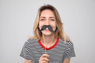 Funny woman with fake mustache on grey background