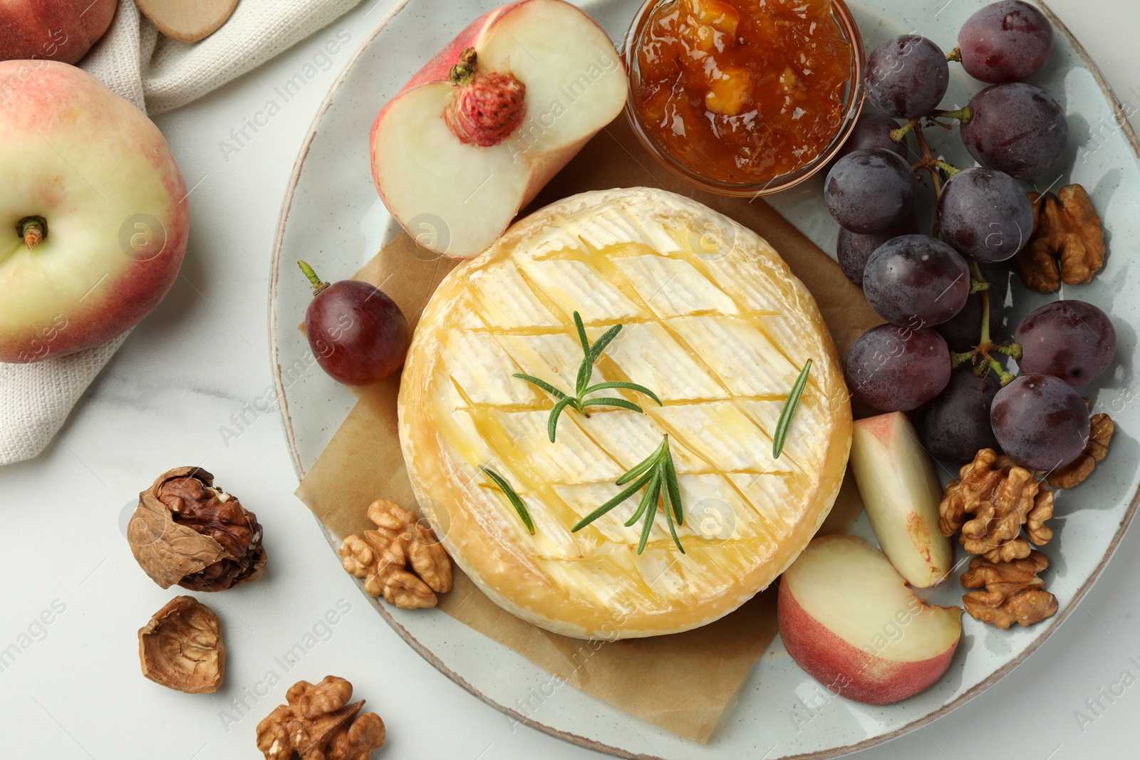 Photo of Tasty baked brie cheese served on white marble table, flat lay