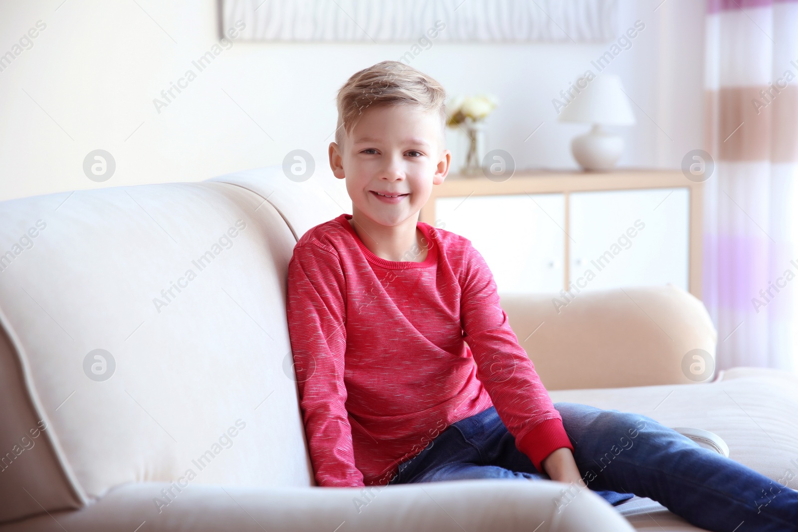 Photo of Cute little boy sitting on sofa, indoors