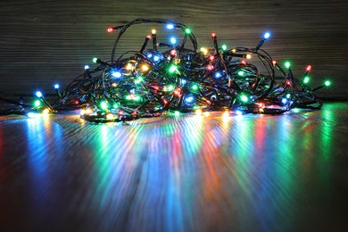 Photo of Beautiful colorful Christmas lights on wooden table. Space for text