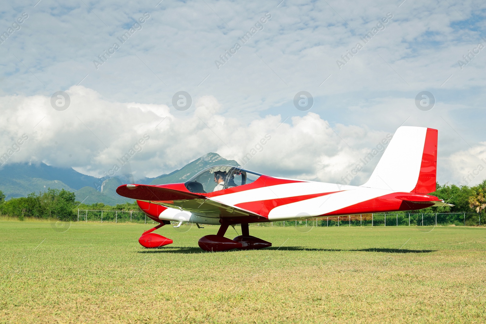 Photo of Modern airplane on green grass against mountains background