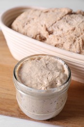 Photo of Fresh sourdough starter and dough on table, closeup