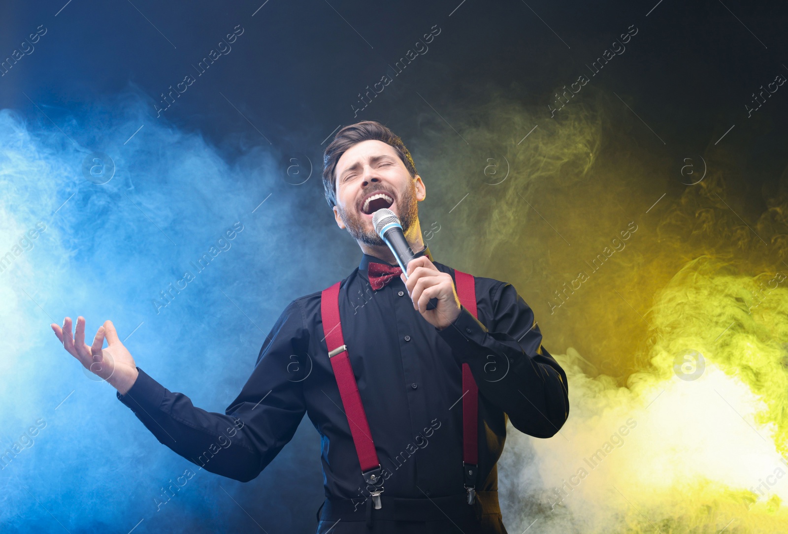 Photo of Emotional man with microphone singing in color lights