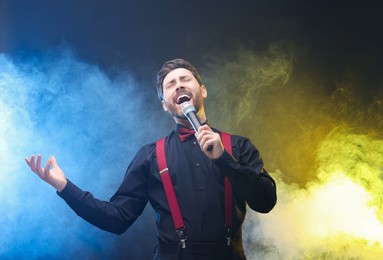 Emotional man with microphone singing in color lights