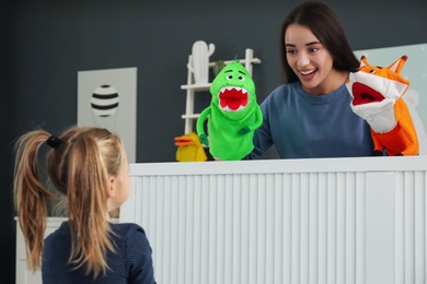 Photo of Mother performing puppet show for her daughter at home
