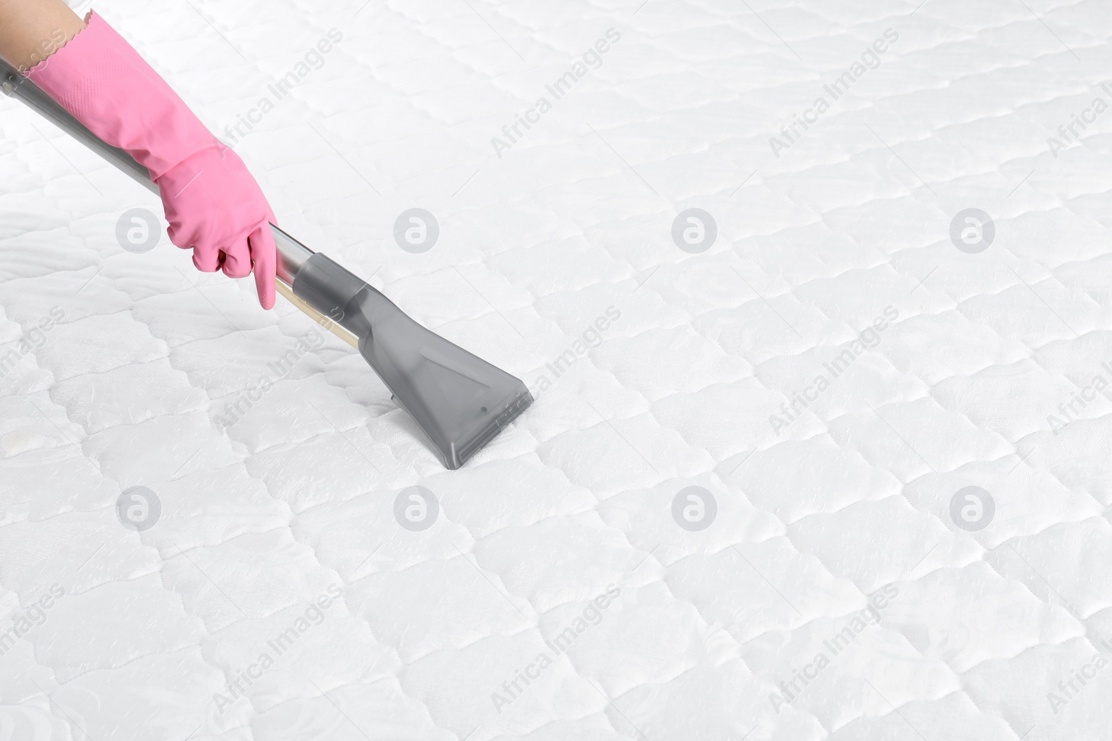 Photo of Woman disinfecting mattress with vacuum cleaner, closeup. Space for text