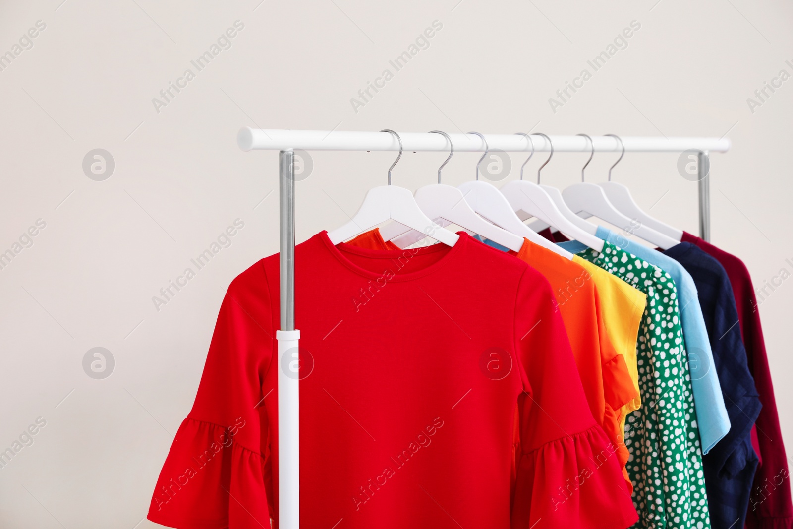 Photo of Wardrobe rack with different bright clothes on light background