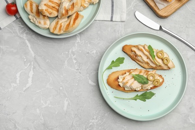 Photo of Plate of delicious chicken bruschettas on grey marble table, flat lay. Space for text