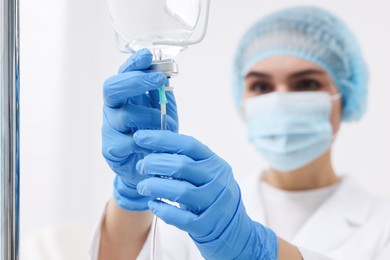 Photo of Nurse setting up IV drip on blurred background, selective focus